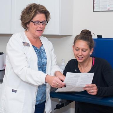 A student going over health paperwork with a U N E nurse